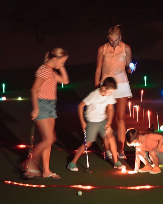 A family putting on a glow-lit green at night