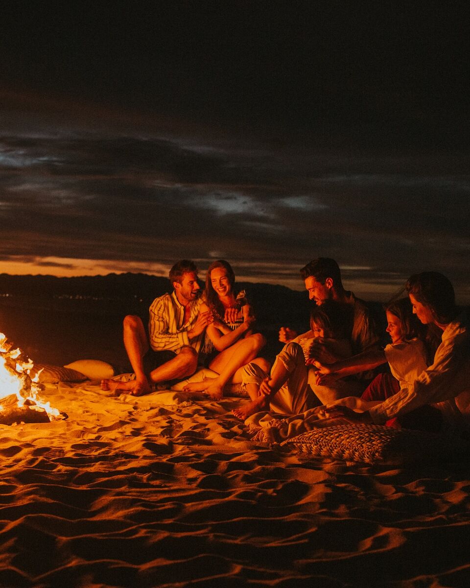 Friends gathered around a beach bonfire at night