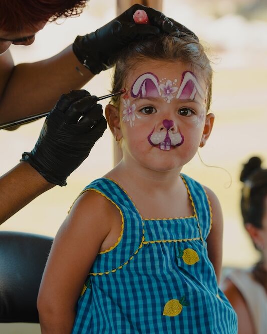 A child getting her face painted as a bunny at the carnival