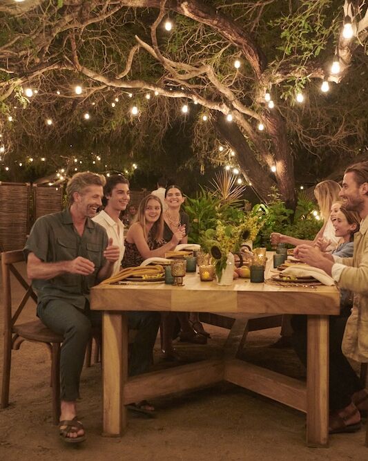 Guests sharing dinner at a long table beneath string lights